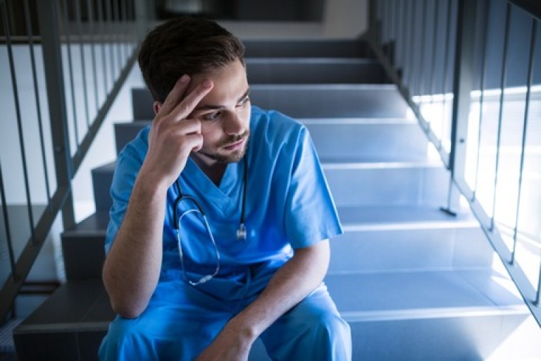 Tensed male nurse sitting on staircase
